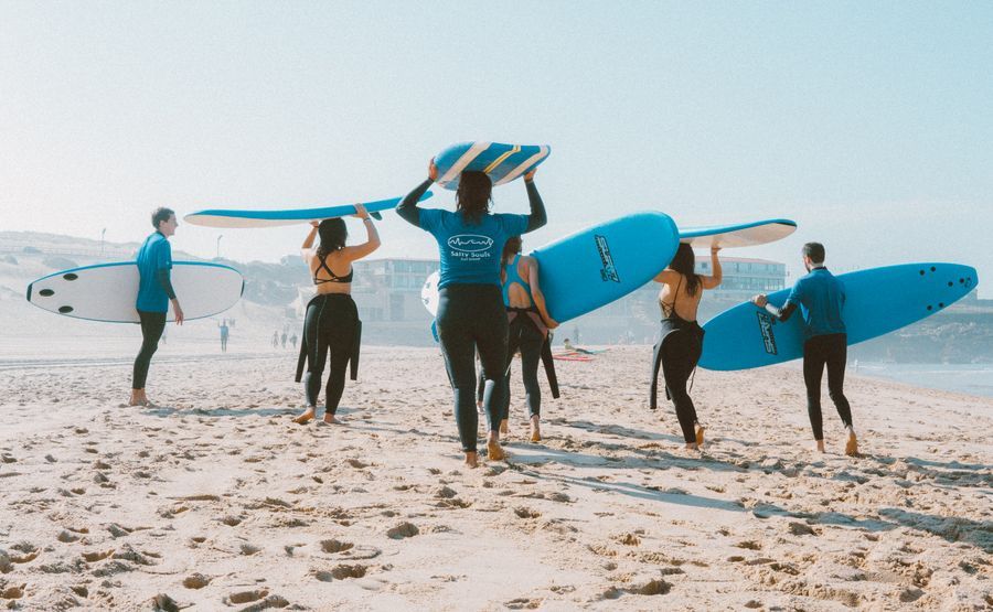 A group carrying boards down to the water for a lesson
